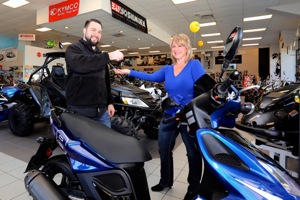 Belinda Phillips looks ready to take over the keys to her KYMCO Scooter from Nate Stickney of Deland Motorsports, Inc.