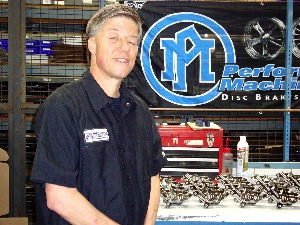 PM President Mark Finnie Standing in front of brake calipers his company manufactures.